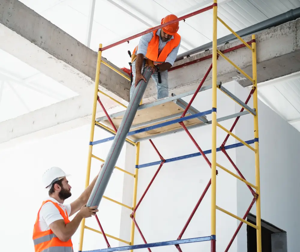 Construction workers handling a metal pipe