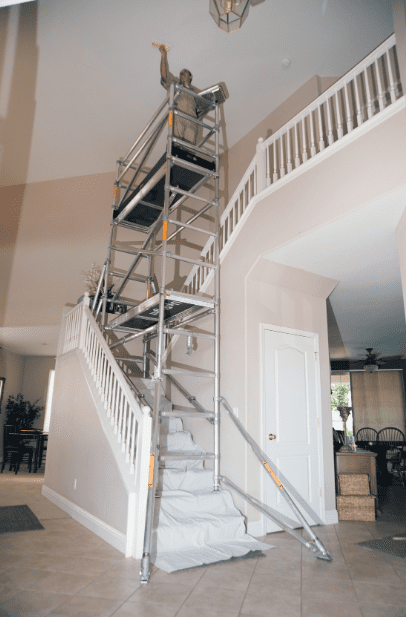 Portable metal scaffolding set up on an indoor staircase for home renovation.