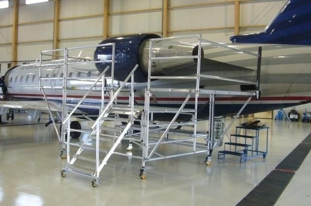 Mobile maintenance scaffold next to an aircraft in a hangar.