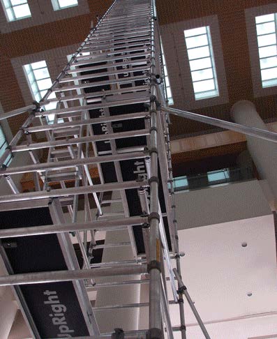 Metal scaffolding structure inside a tall building with windows.