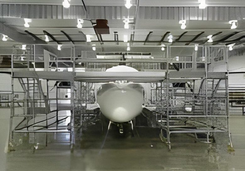 Front view of a white aircraft under maintenance in a hangar.