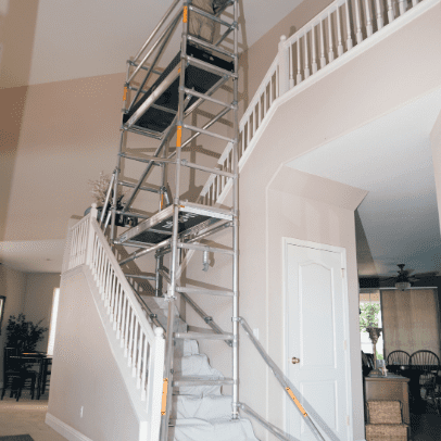 Portable metal scaffolding set up on an indoor staircase for home renovation.